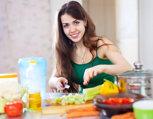 Beautiful woman cuts green celery — Stock Photo, Image