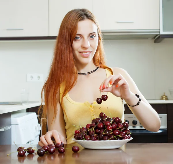 Young woman with cherries in kitchen — Stock Photo, Image