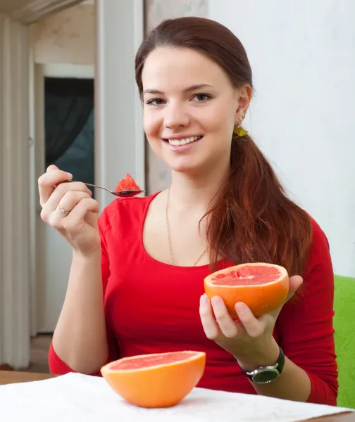 Bella ragazza in rosso mangia pompelmo — Foto Stock