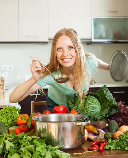 Positive Frau kocht mit Schöpfkelle aus rohem Gemüse lizenzfreie Stockbilder