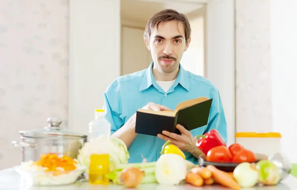 Retrato de homem com livro de receitas na cozinha doméstica — Fotografia de Stock