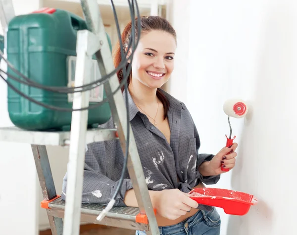 Woman in grey shirt paints wall with roller — Stock Photo, Image