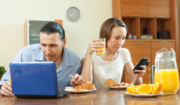 Couple using devices during breakfast time — Stock Photo, Image