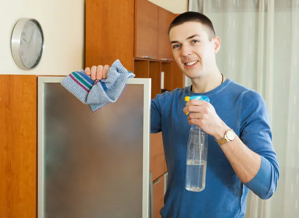 Mann putzt Glas zu Hause mit Lappen und Reinigungsmittel — Stockfoto