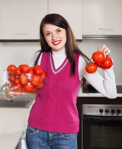 Щаслива жінка з червоними помідорами на кухні — стокове фото
