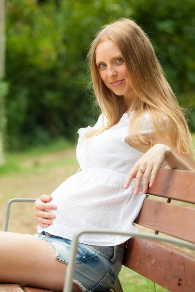 Szczęśliwy ciąży kobieta na ławce — Zdjęcie stockowe