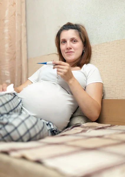 Pregnant woman holding thermometer Stock Picture