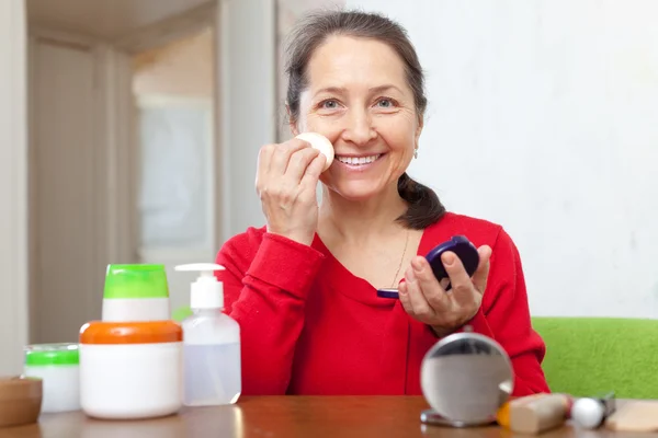 Volwassen vrouw in jurk zet facepowder op gezicht — Stockfoto