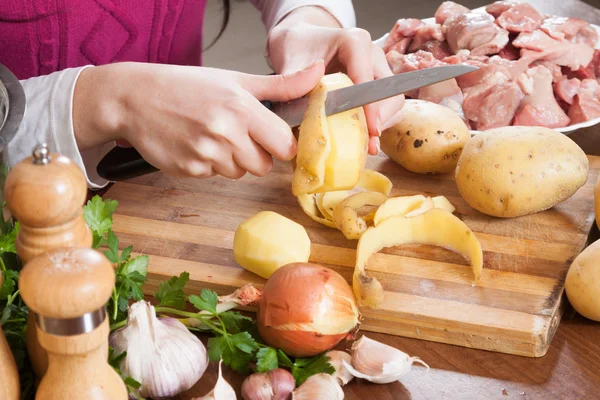 Händer rengöring potatis på bordet i köket — Stockfoto