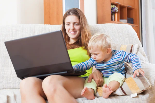 Sorridente madre con bambino che lavora online — Foto Stock