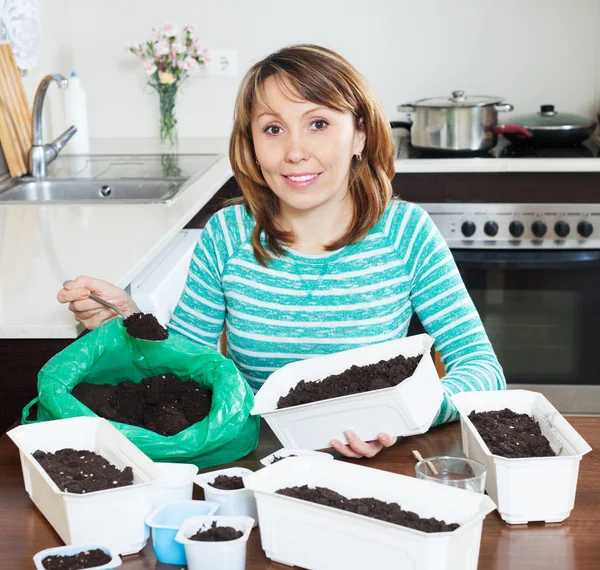 Woman in green making soil for seedlings — Stock Photo, Image