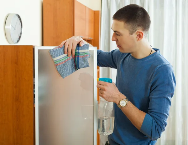 Mann putzt Glas zu Hause mit Lappen und Reinigungsmittel — Stockfoto