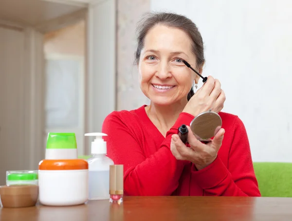 Glücklich reife Frau legt Wimperntusche auf — Stockfoto