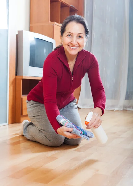 Mature housewife polishing parquet floor — Stock Photo, Image