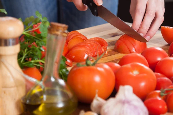 Hände schneiden Tomaten am Tisch — Stockfoto