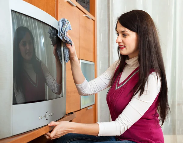 Mujer limpiando el polvo en la televisión en la sala de estar —  Fotos de Stock