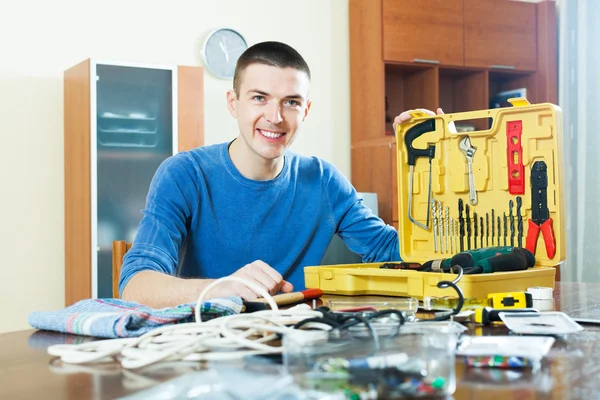 Bel homme souriant assis par boîte à outils — Photo