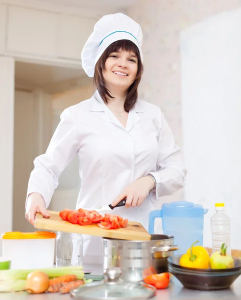 Позитивная домохозяйка готовит с помидорами — стоковое фото