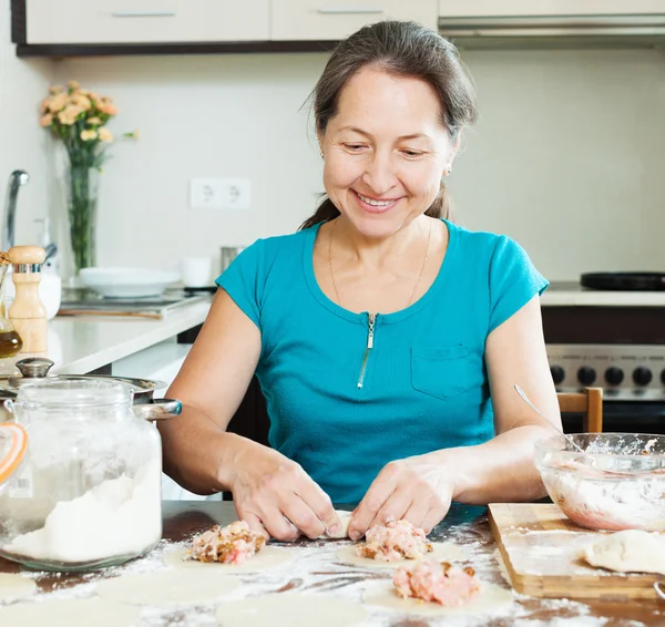 Mature housewife making meat dumplings — Stock Photo, Image