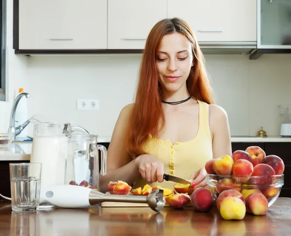 Long-haired girl in yellow  with peaches at home — Stock Photo, Image