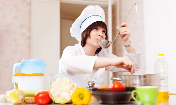 Female cook  tasts soup from salt — Stock Photo, Image