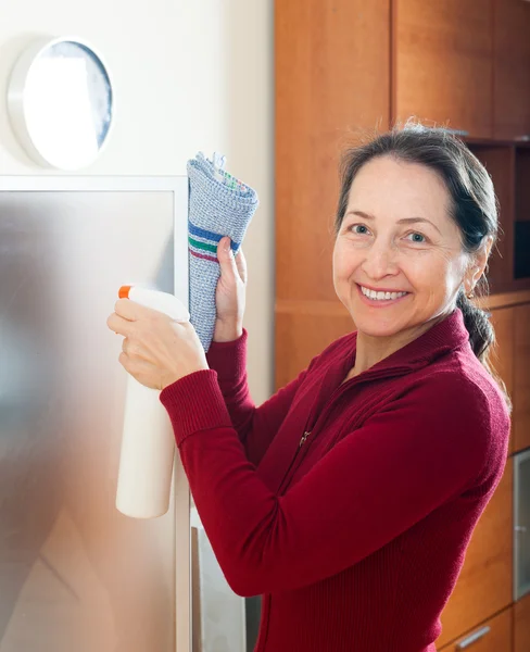 Glimlachende volwassen vrouw schoonmaken glas — Stockfoto