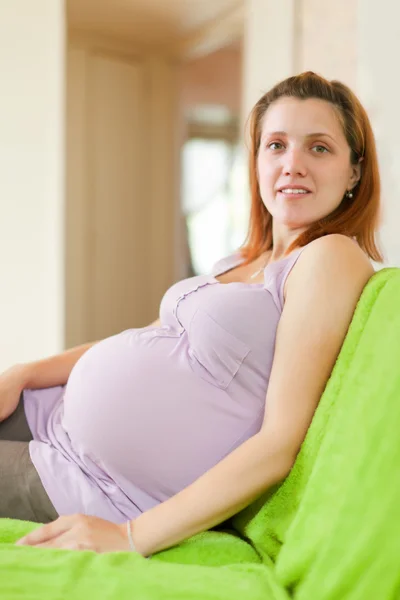 Zwangere vrouw op sofa in huis — Stockfoto