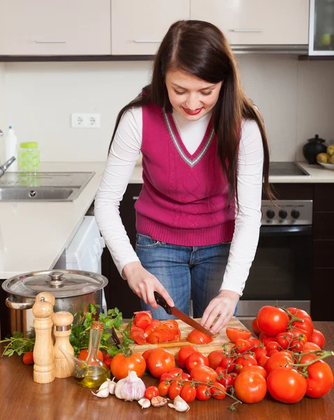 Brunette femme au foyer aux cheveux longs cuisine avec des tomates — Photo