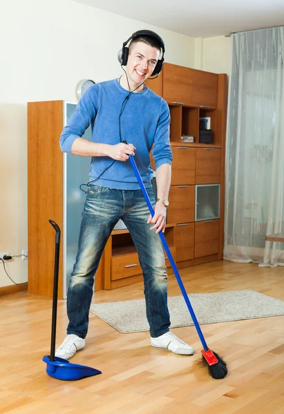 Handsome man with broom and dustpan at home — Stock Photo, Image