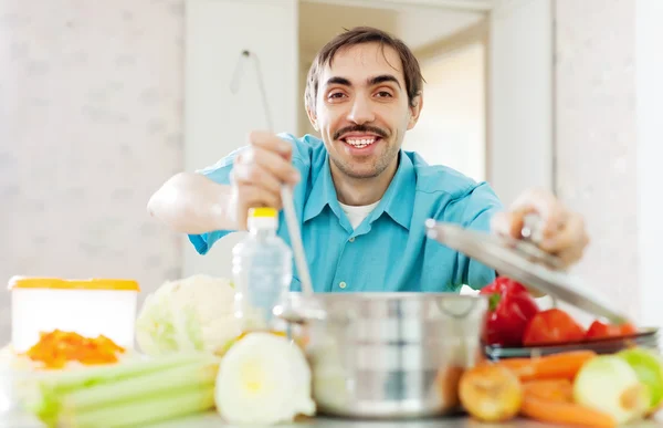 Feliz homem bonito cozinha almoço — Fotografia de Stock