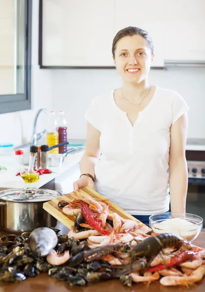 Молодая улыбающаяся домохозяйка с сырыми морепродуктами — стоковое фото