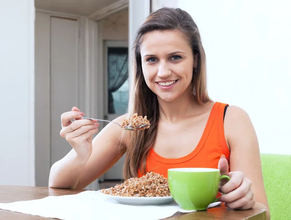Woman eats buckwheat porridge — Stok fotoğraf