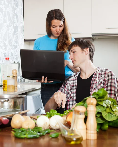 Paar kijken laptop tijdens het koken van voedsel — Stockfoto