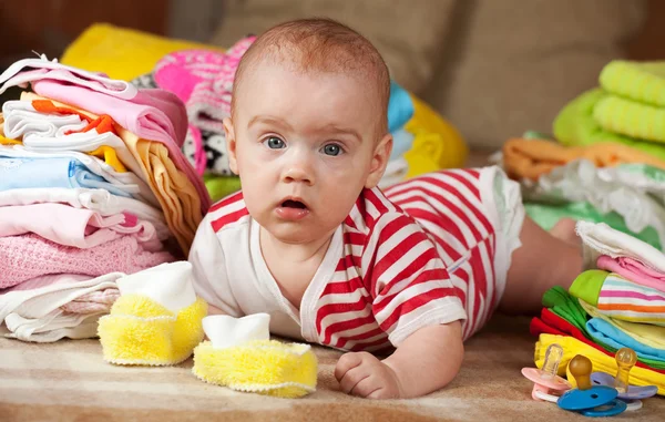 Baby  with heap of children's wear — Stock Photo, Image