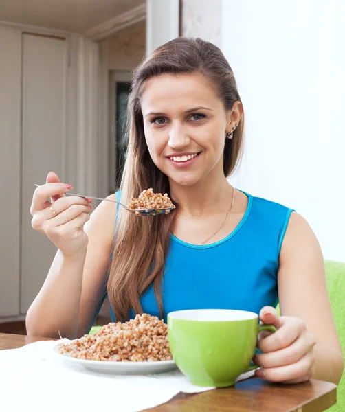 Donna sorridente mangia grano saraceno — Foto Stock