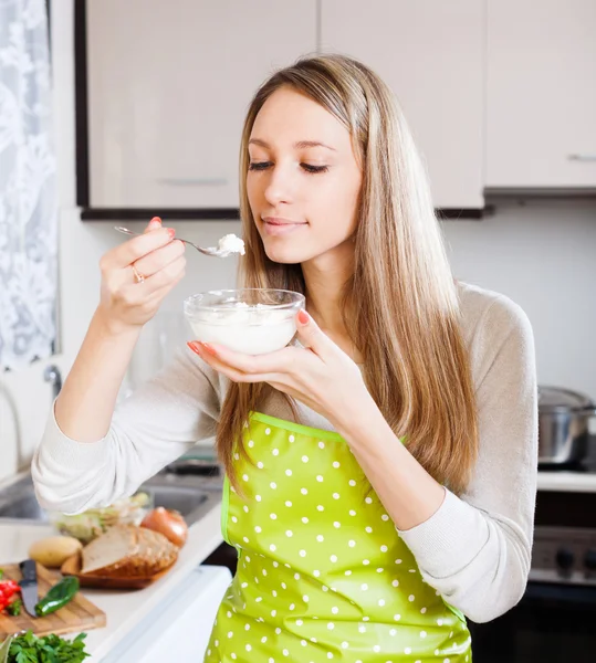 Woman in apron eating curd cheese — Stock Photo, Image