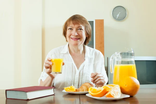 Reife Frau frühstückt mit Buch — Stockfoto