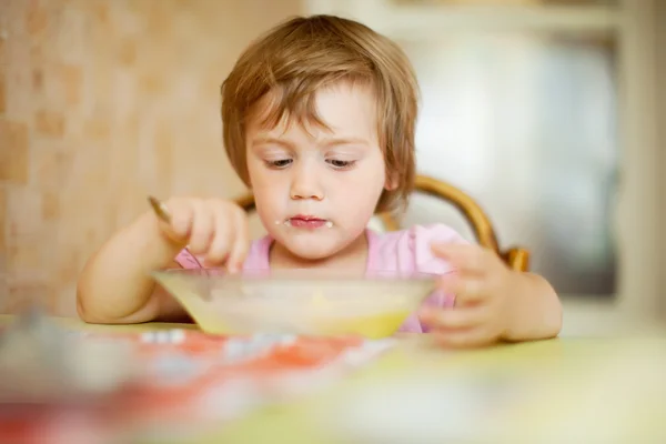 Child eats with spoon in home — Stock Photo, Image