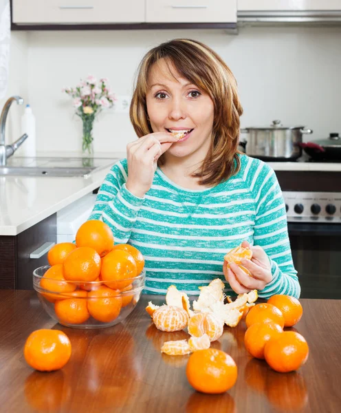 Chica positiva comiendo mandarina en casa —  Fotos de Stock