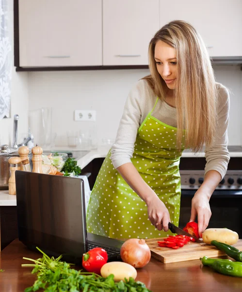 Kvinna som använder bärbar dator under tillagningen — Stockfoto