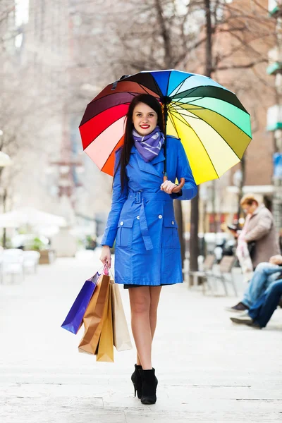 Vrouw met boodschappentassen en paraplu — Stockfoto