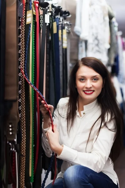 Meisje kiezen riem bij shop — Stockfoto