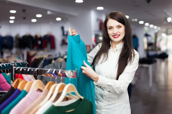 Joyful female buyer choosing sweater — Stock Photo, Image