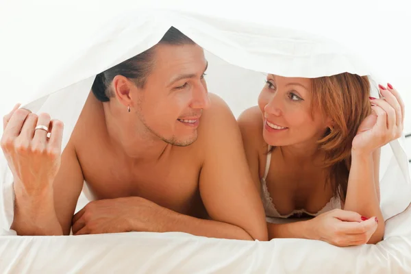 Pareja feliz jugando en la cama — Foto de Stock