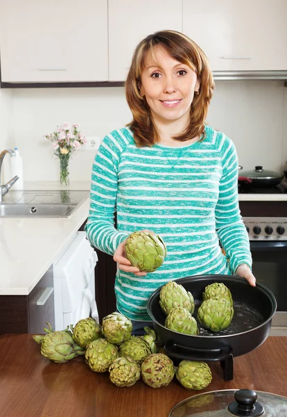 Lyckliga hemmafrun matlagning kronärtskockor — Stockfoto