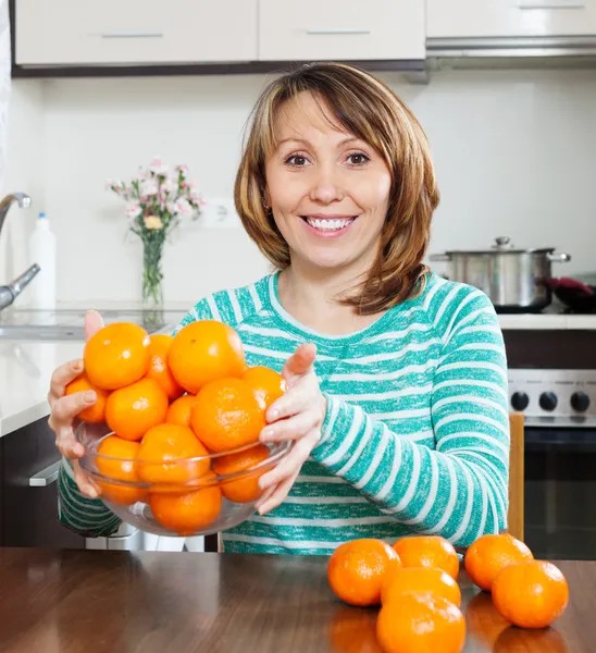 Mulher feliz segurando monte de mandarinas — Fotografia de Stock
