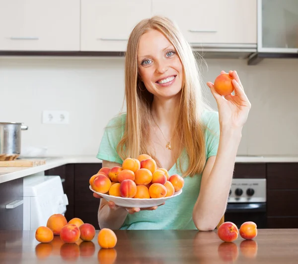 Hemmafru med högen av aprikoser på kök — Stockfoto