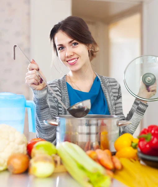 Donna felice cucina zuppa di verdure — Foto Stock