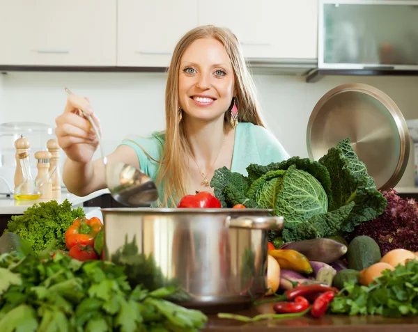 Blond långhårig hemmafru matlagning med slev — Stockfoto