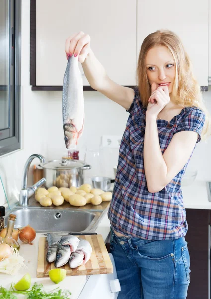 Joven ama de casa pensando cómo cocinar lubina — Foto de Stock